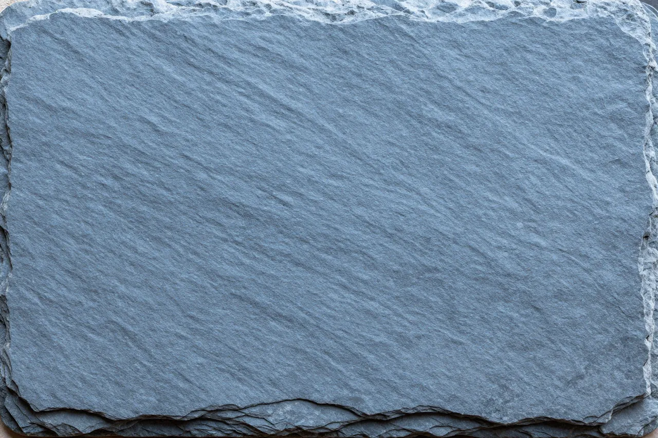 Full frame close-up of flat clefted blue-gray slate with rough layered uneven edges
