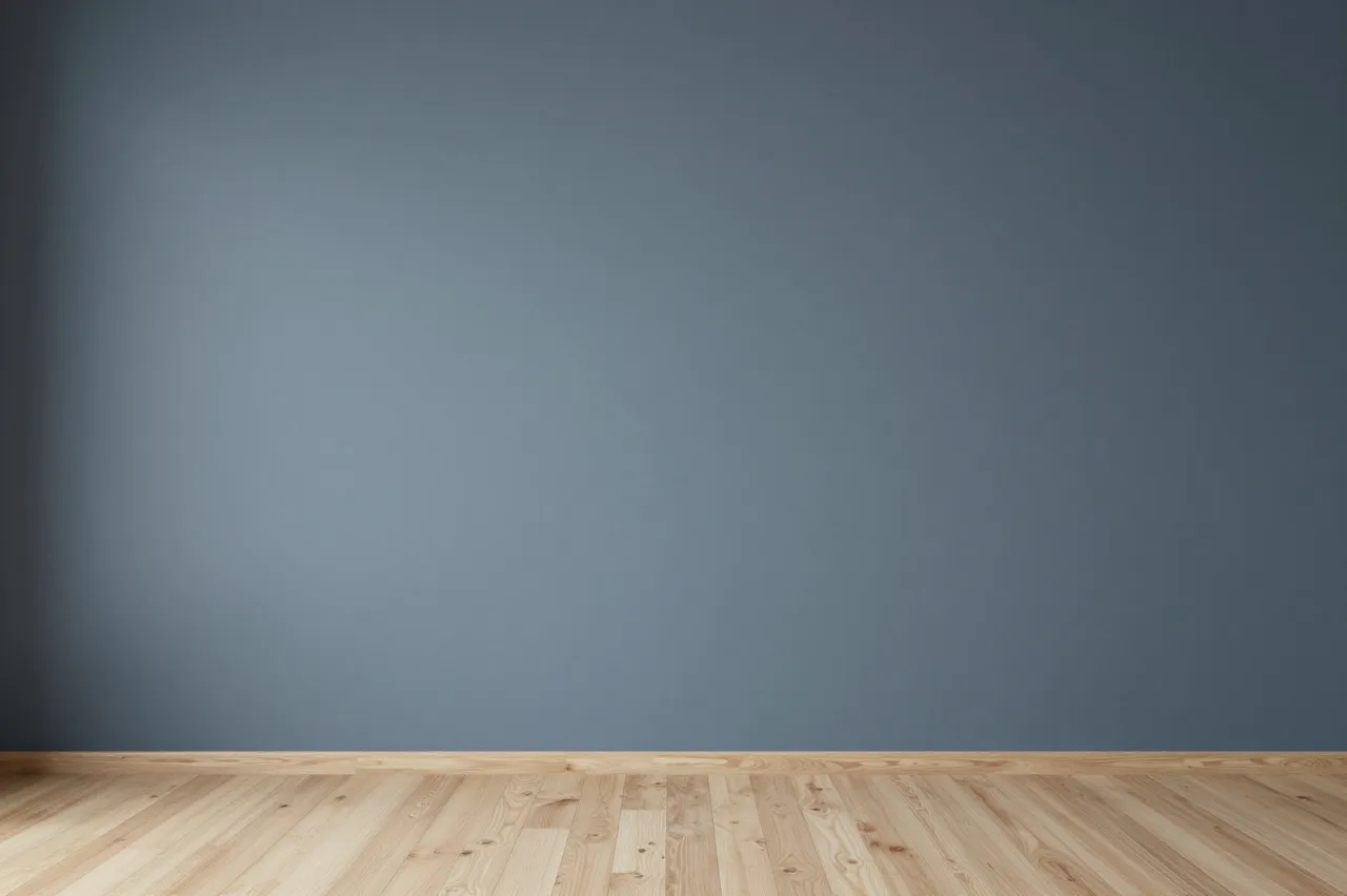 Empty mottled blue grey studio wall with soft vignette sits above a pale wooden floor