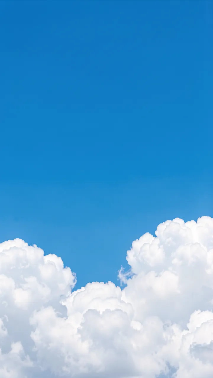 Bright vertical sky blue frame with fluffy white cumulus clouds clustered along the bottom edge and empty clear space above.