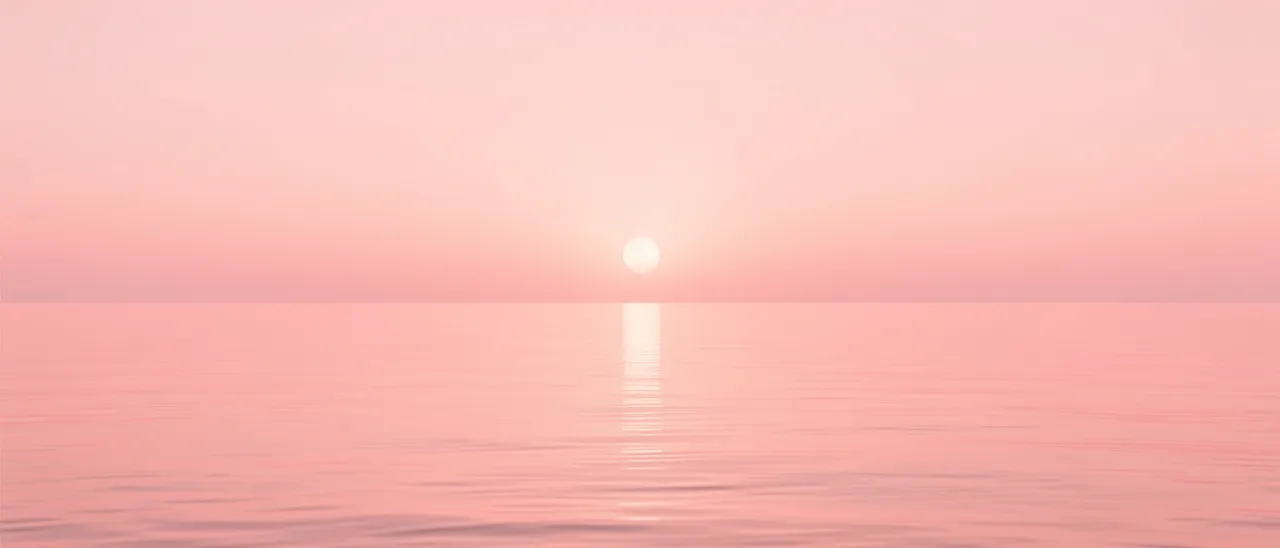 A faint low sun sits over calm pink water beneath a matching soft pink hazy sky