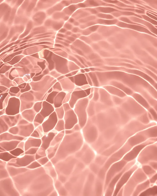 Rippled caustic light reflections flow across a soft blush pink water surface