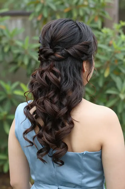 Rear view of a woman showing an elegant curled braided updo wearing a dusty blue dress outdoors
