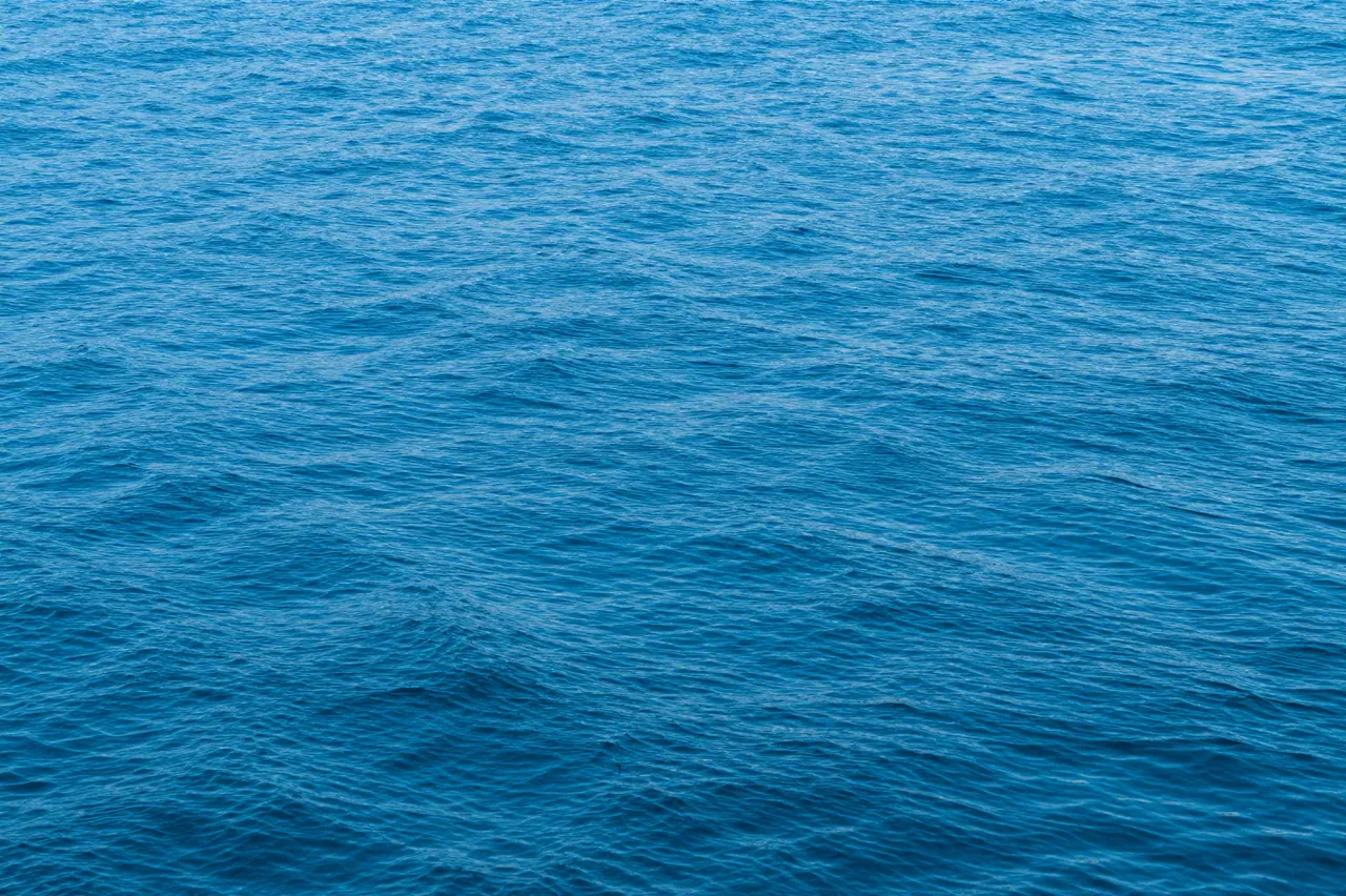 Calm bright blue water surface covered in soft, subtle natural ripples