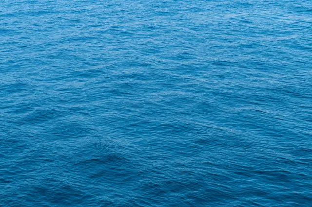 Calm bright blue water surface covered in soft, subtle natural ripples