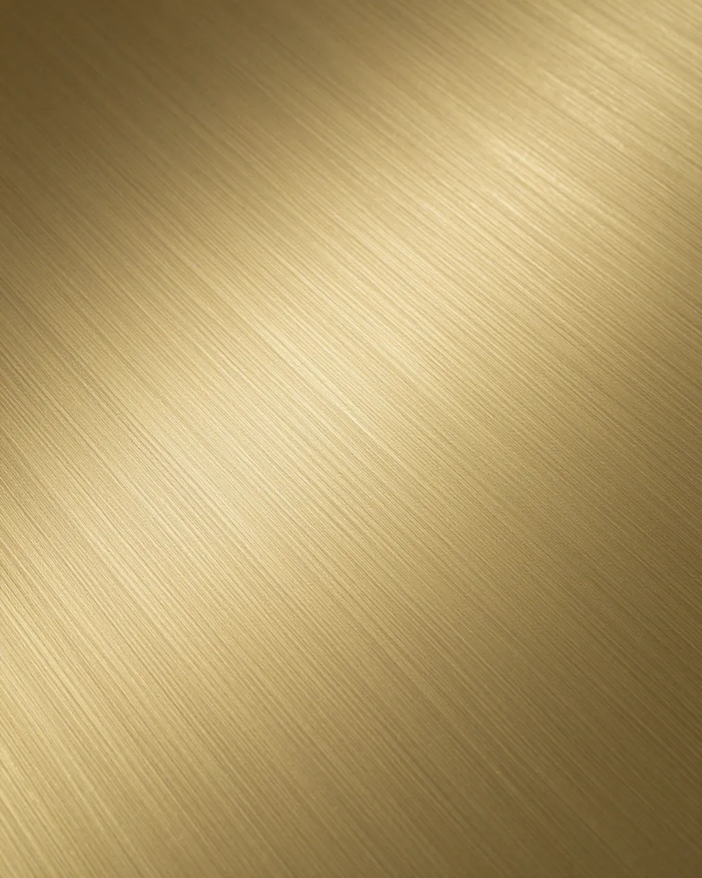 Full frame close-up of satin brushed brass metal with fine diagonal grain and soft gradient lighting