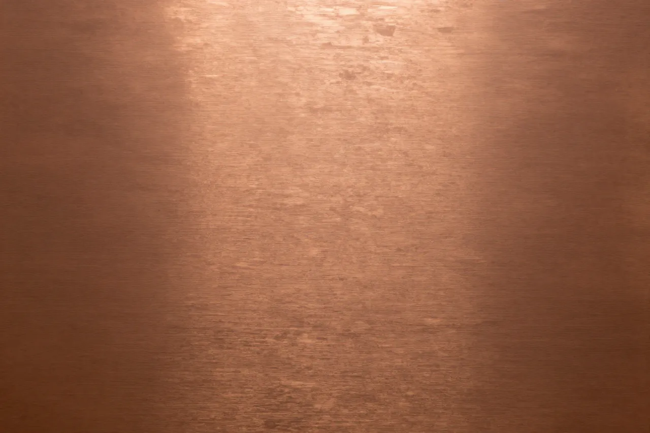 Warm brushed copper metal surface with subtle directional grain and soft center highlight