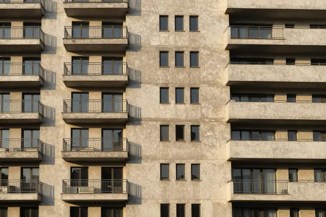 Concrete brutalist apartment building facade with repeating balconies lit by warm golden hour sunlight