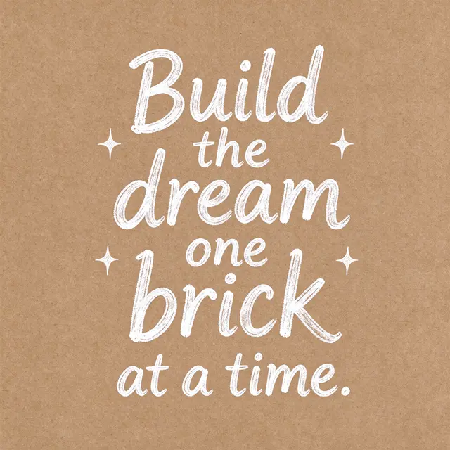 White hand lettering reading "Build the dream one brick at a time." with small star doodles on brown kraft paper.