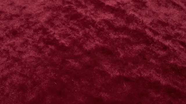 Full frame close-up of soft burgundy velvet fabric with subtle brushed nap variations