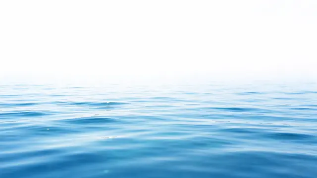Gentle rippled bright blue water transitions to empty bright white upper copy space