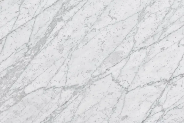 Full frame close-up of cool white Carrara marble with soft gray feathery veining under even flat light