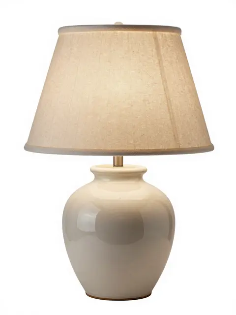A glossy cream ceramic table lamp with a pleated linen shade sits against a pure white background