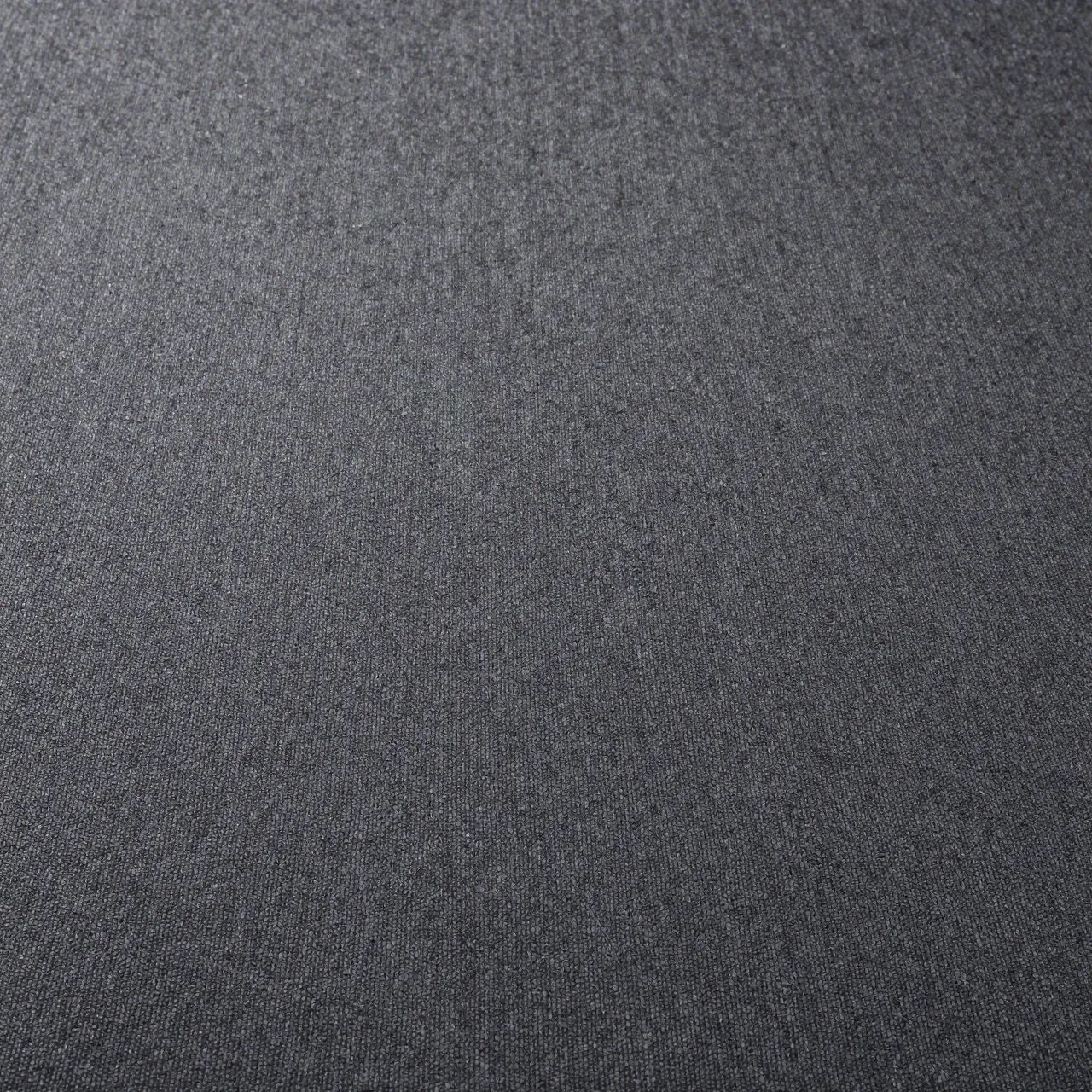 Close-up top view of fine textured low-pile charcoal carpet under flat even lighting