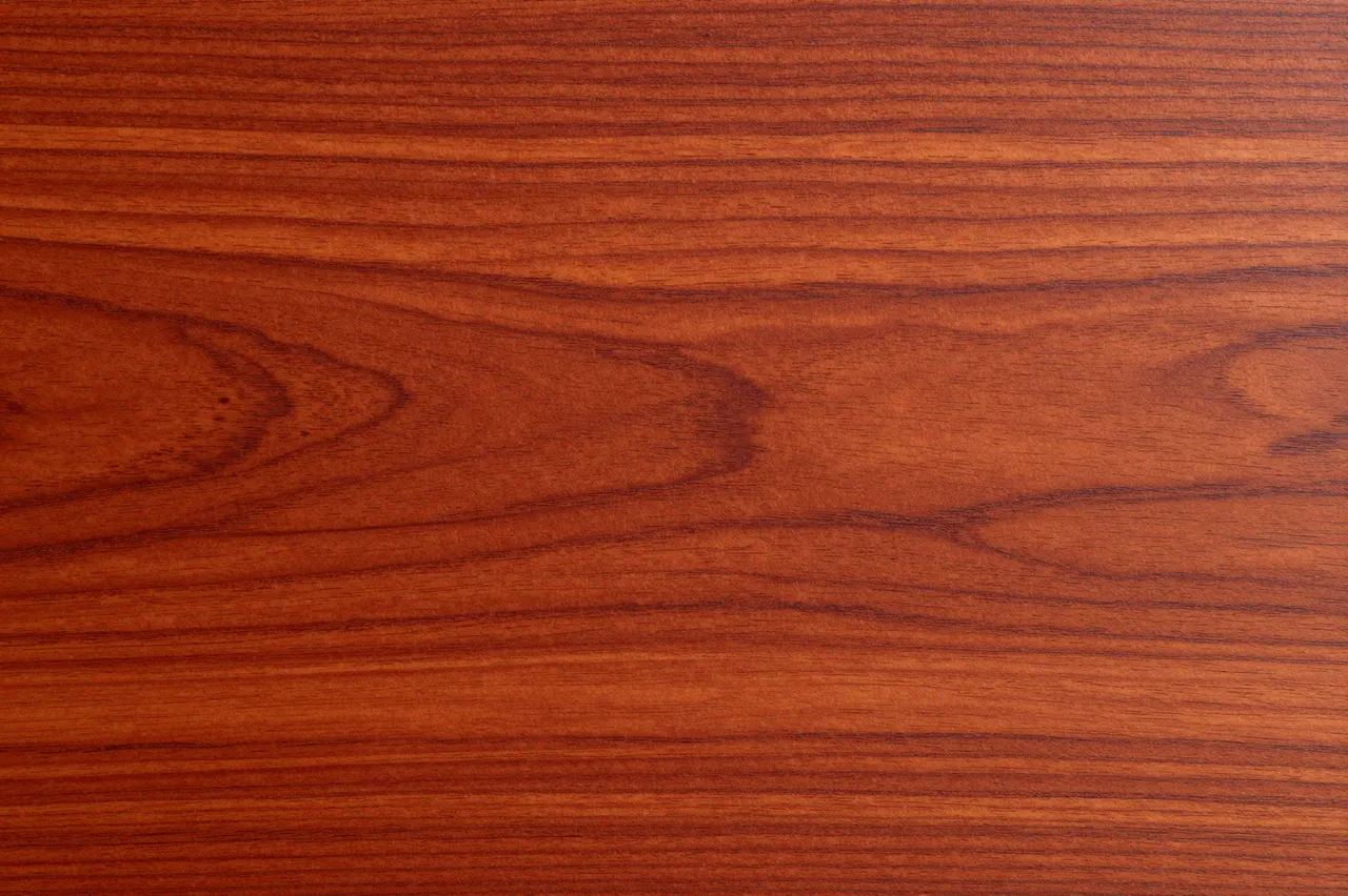 Full frame close-up of smooth cherry wood with warm reddish horizontal grain patterns