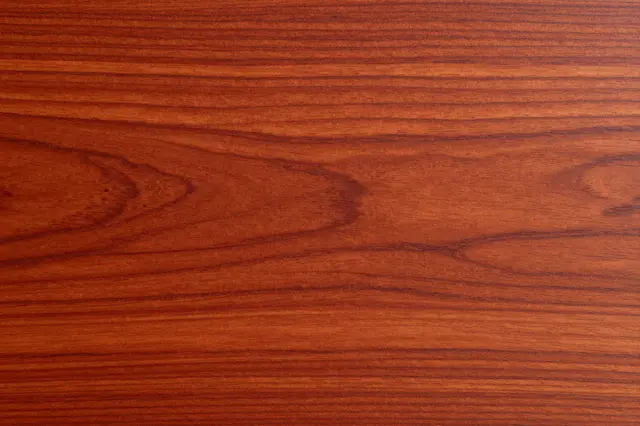 Full frame close-up of smooth cherry wood with warm reddish horizontal grain patterns