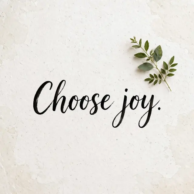 Black brush script reading "Choose joy." sits next to a small green leaf sprig on textured off-white watercolor paper