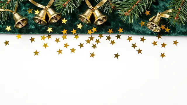 Top border of pine branches, gold bells, star confetti on emerald velvet above empty white copy space