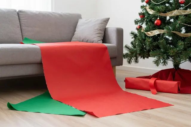 Festive living room with decorated Christmas tree and discarded red and green wrapping paper on the floor