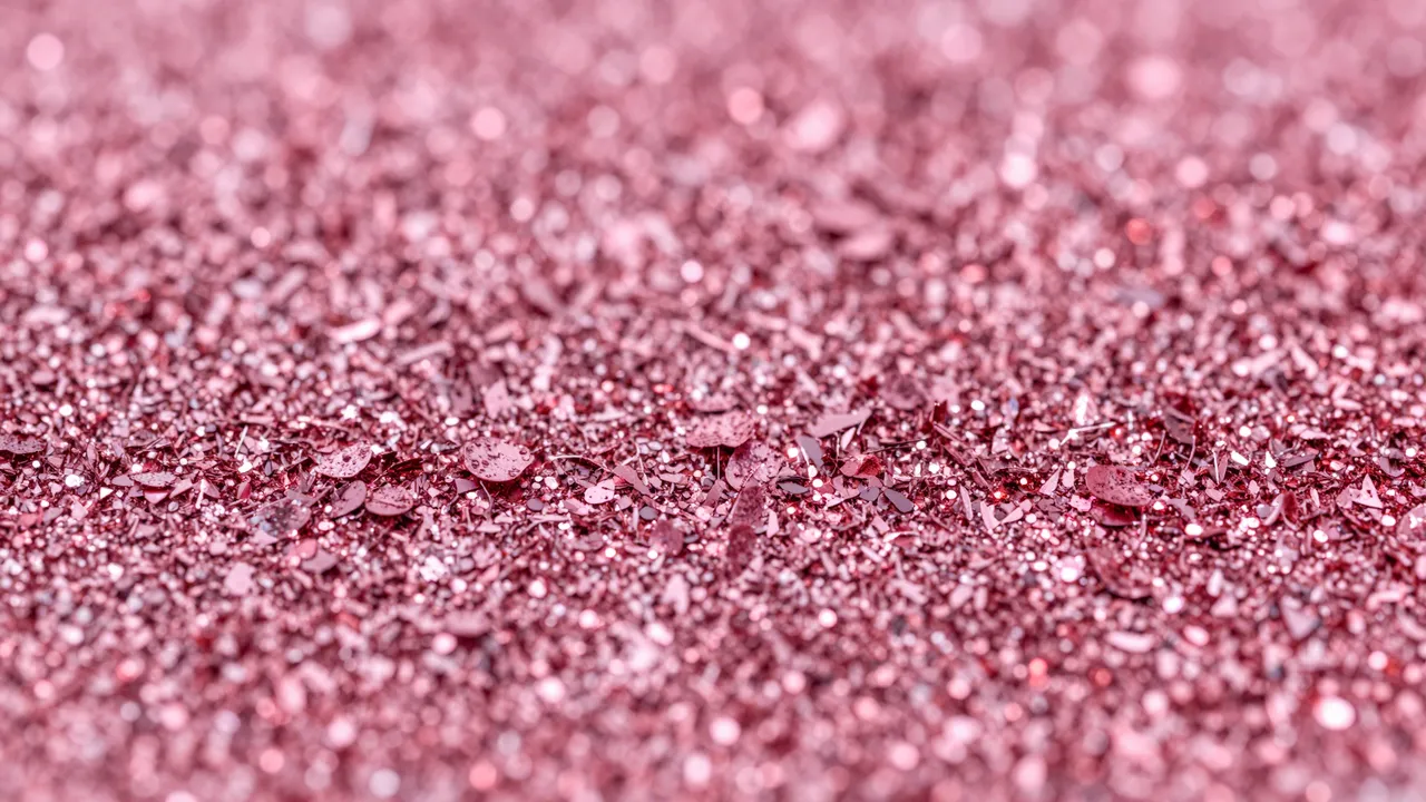 Close-up of dense rose and hot pink glitter flakes with sparkling highlights and shallow depth of field