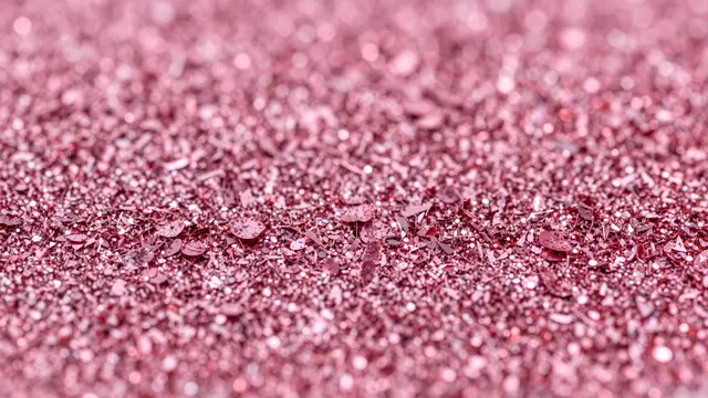 Close-up of dense rose and hot pink glitter flakes with sparkling highlights and shallow depth of field