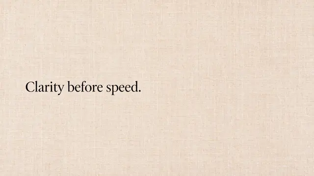 The text "Clarity before speed." in black serif type sits left-aligned on a warm beige linen textured desktop background