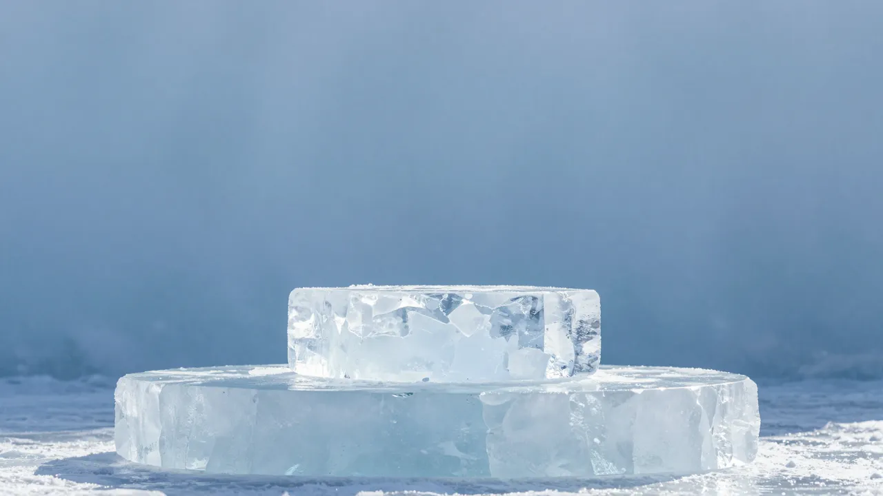 Stacked clear ice block podium sits against a soft frosty blue backdrop with ample copy space