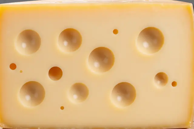Close-up view of a pale yellow block of swiss cheese with characteristic round holes across its cut surface