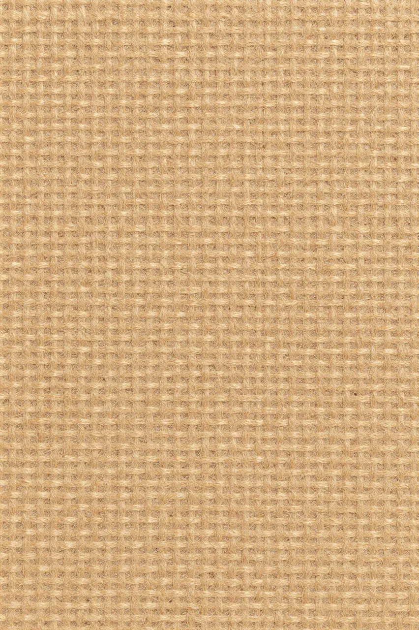 Full frame close-up of a natural tan woven jute fiber surface with flat even lighting