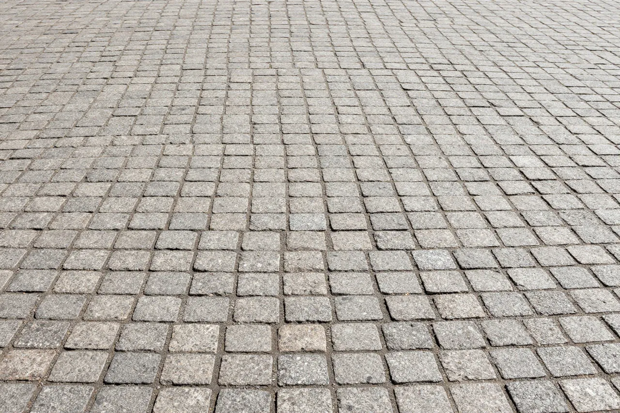 Diagonal perspective view of uniform light gray cobblestone pavement extending across the frame