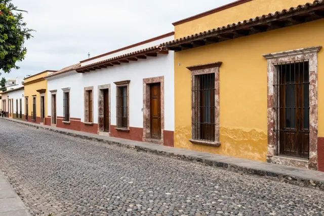 A quiet cobblestone street lined with colorful colonial buildings under an overcast sky
