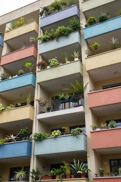 Low angle view of a modern apartment building with brightly colored balconies filled with potted greenery