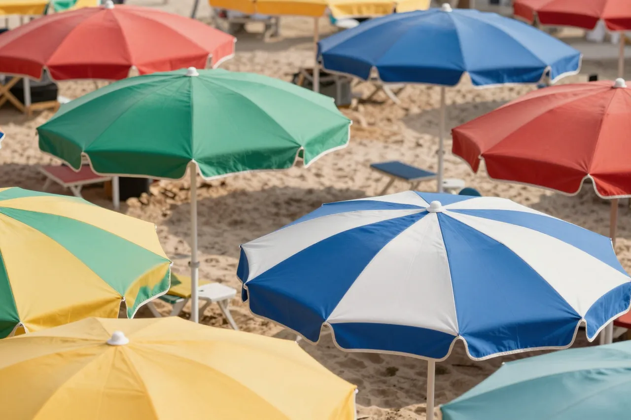 Bright varied beach umbrellas arranged across sunlit sandy shore seen from an overhead perspective