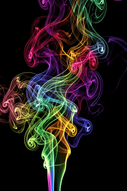 Vibrant multicolored wispy smoke swirls and curls against a solid black background