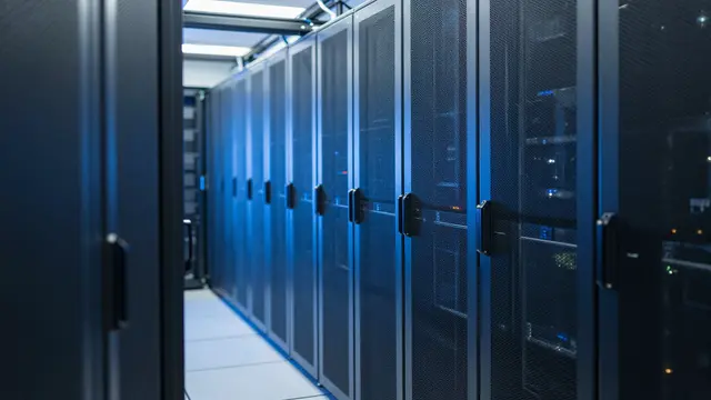 Long aisle between rows of enclosed server racks lit with cool blue lighting in a data center