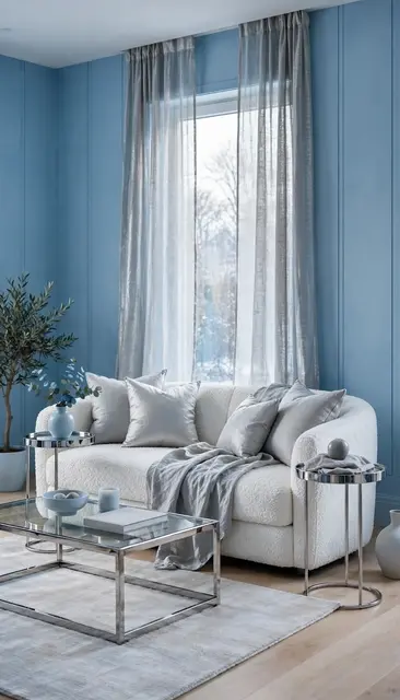 Stylish icy blue living room with a white bouclé sofa and chrome furniture arranged near a tall window.