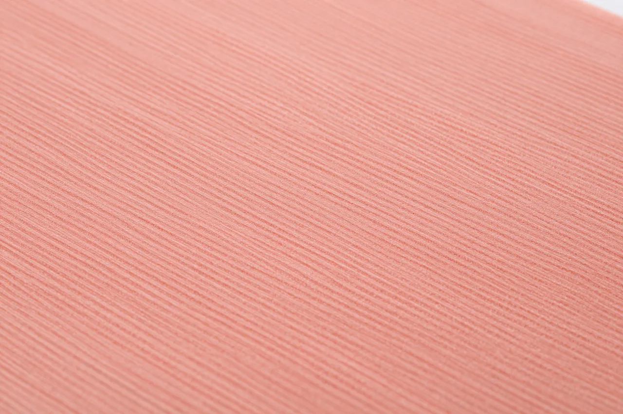 Close-up full-frame view of fine ridged coral crepe paper with flat even lighting