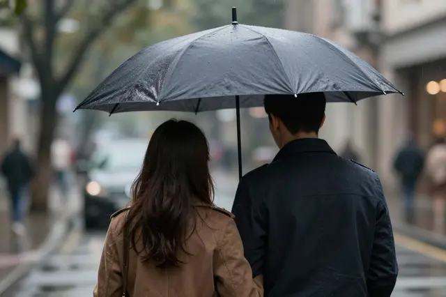 Back view of a couple walking together under a black umbrella on a rainy city street