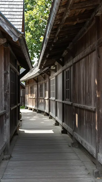 Dappled noon sunlight falls on a narrow covered wooden passage between traditional wooden village buildings