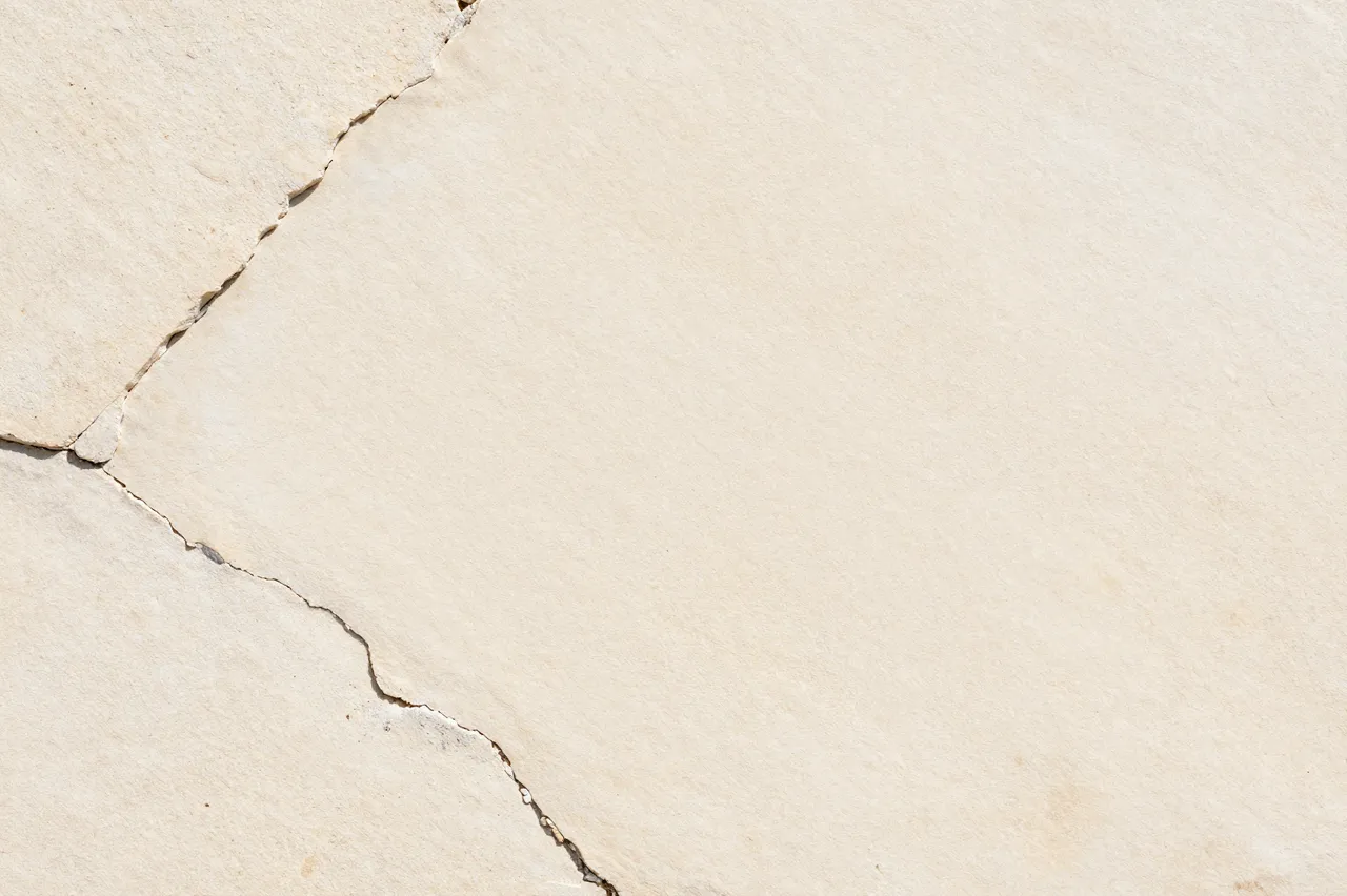 Full frame close-up of pale cream limestone with natural cracks and a rough matte surface
