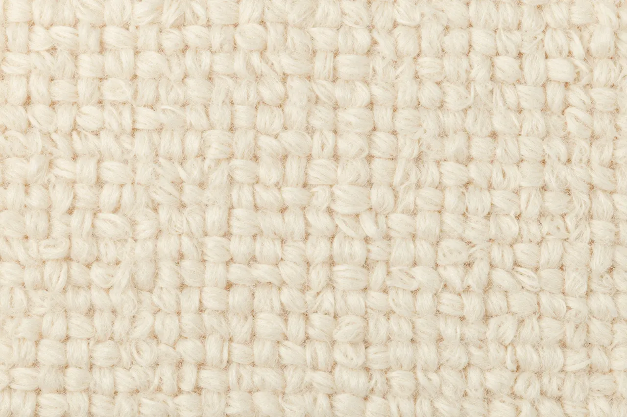 Full frame close-up of soft cream looped boucle fabric surface showing its textured yarn structure