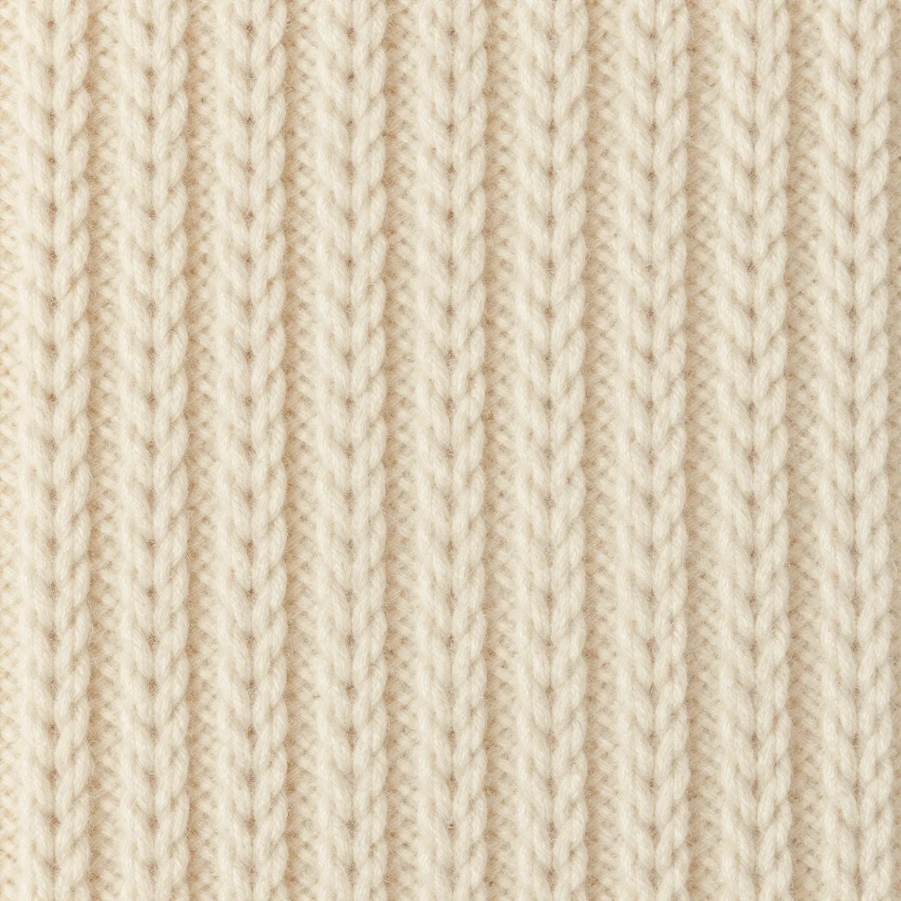 Full frame close-up of even ribbed chunky cream wool knit fabric under flat soft light
