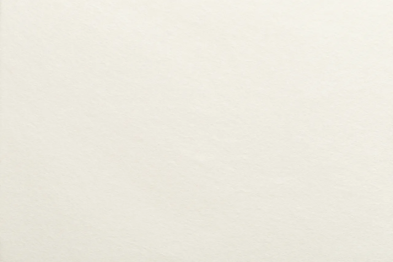 Full frame close-up of smooth cream cotton paper with a subtle fine tooth texture