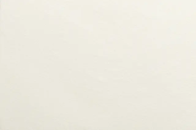 Full frame close-up of smooth cream cotton paper with a subtle fine tooth texture