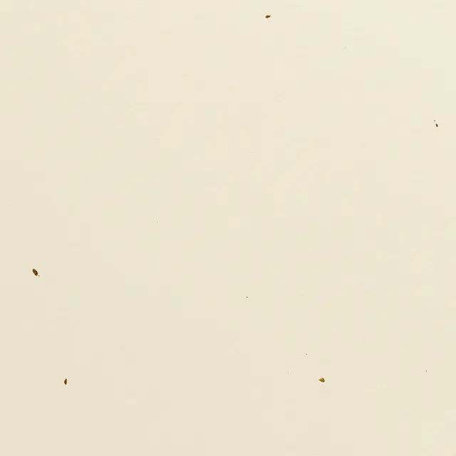 Full frame view of smooth cream handmade paper scattered with tiny gold leaf flecks under even light