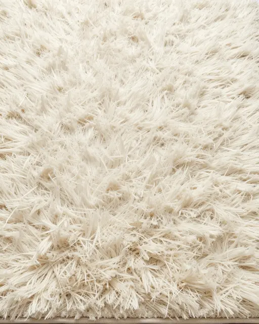 Close-up top view of soft long-pile cream shag rug under even lighting