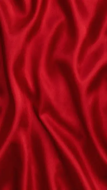 Vertical close-up of rippled deep crimson satin fabric with soft folded light gradients
