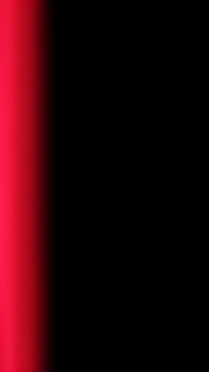 A smooth vertical crimson gradient light leak runs along the left edge of a pure black background