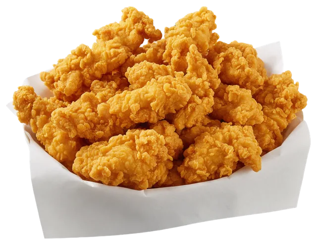 Piled golden crispy fried chicken strips sit in a plain white paper lined basket