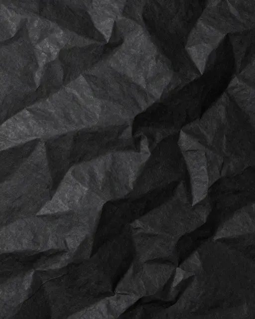 Full frame close-up of crumpled black paper with subtle sheen on raised ridges