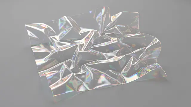 Crumpled clear iridescent film with rainbow light refraction rests against a smooth soft gray background